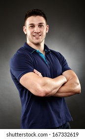 Studio Shot Of Handsome Young Man Wearing A Navy Blue Polo T-shirt With Arms Folded