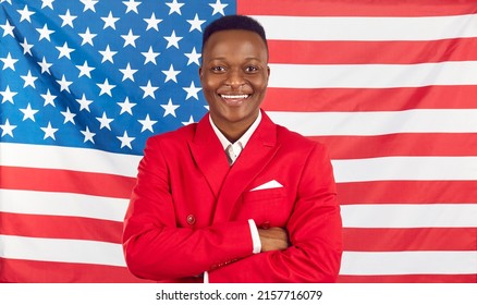 Studio shot of happy African American man standing with his arms crossed on stars and stripes background. Attractive ethnic Tanzanian immigrant in red jacket poses with arms folded against flag of USA - Powered by Shutterstock