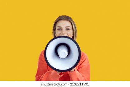 Studio Shot Of Happy Beautiful Young Woman Speaking Or Shouting In Megaphone. Pretty College Or University Student Girl With Loudspeaker Making Important Announcement Isolated On Colour Background