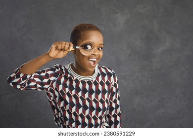 Studio shot of happy black woman with magnifying glass looking at you with funny big eye. Young lady looking for something interesting, searching for fascinating wow facts, making amazing discoveries - Shutterstock ID 2380591229