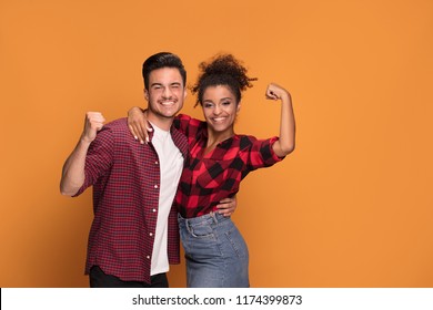 Studio Shot Of Happy Casual Mixed Race Couple Embracing, Posing To Camera And Smiling .