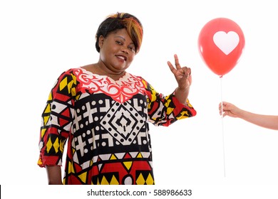 Studio Shot Of Happy Fat Black African Woman Smiling While Giving Peace Sign To Red Balloon With Heart Sign