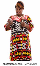 Studio shot of happy fat black African woman smiling and using mobile phone while holding bottle of beer