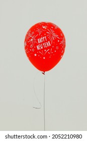 Studio Shot Of Happy New Year Festival Celebration Party Floating Helium Inflatable Firework Confetti And Star Pattern Red Balloon Flying With String Weighted On Small Sandbag On White Background.