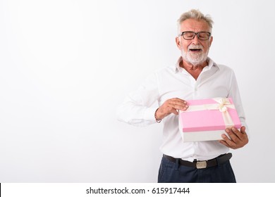 Studio Shot Of Happy Senior Bearded Man Smiling While Opening Gift Box Eyes Closed Against White Background