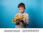 the studio shot isolated image of the boy playing the miniture airplane with the blue backdrop