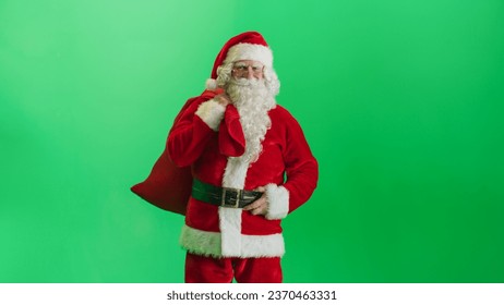 Studio Shot Isolated Mockup Template: Jolly Santa Claus Standing On Green Screen Chromakey Background And Holding Bag With Gifts, Looking at Camera. Christmas, New Year, Holiday Celebration. Zoom Out - Powered by Shutterstock