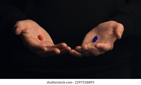 Studio shot male hands show red pill and blue pill isolated on black background. Concept of making right choice.