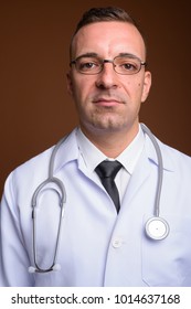 Studio shot of man doctor wearing eyeglasses against brown background