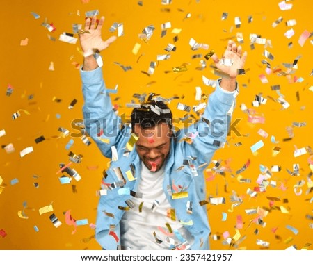 Studio Shot Of Man With Down Syndrome Celebrating Big Win Showered In Tinsel Confetti
