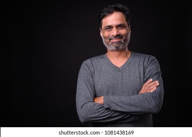 Studio Shot Of Mature Bearded Indian Man Against Black Background