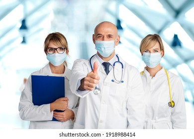 Studio Shot Of Medical Team Wearing Face Masks For Prevention And Male Doctor Showing Thumbs Up While Standing At The Clinic. 