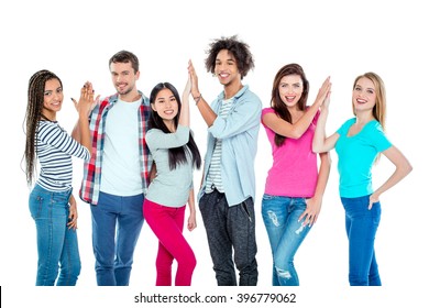 Studio shot of nice young multicultural friends. Beautiful people making high fives, looking at camera and cheerfully smiling. Isolated background