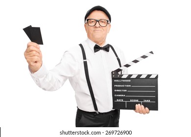 Studio Shot Of An Older Movie Director Holding A Clapperboard And Two Tickets Isolated On White Background