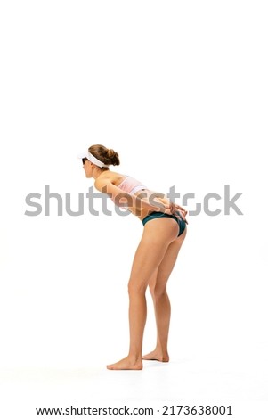 Studio shot of one fitness young woman, volleyball player in sports swimsuit playing beach volleyball isolated on white background. Sport, team, fitness concept. Vacation, summer sports games