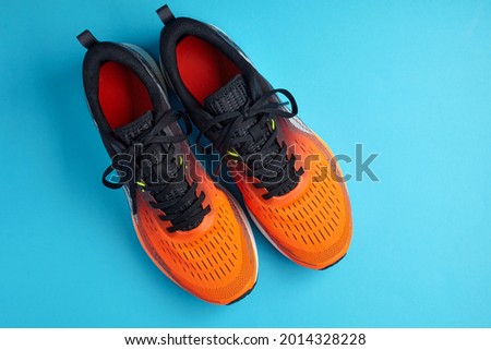 A studio shot of orange sneakers on a blue background