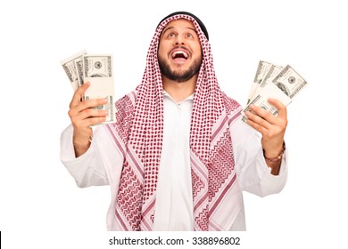 Studio shot of an overjoyed Arab holding stacks of money and looking up isolated on white background