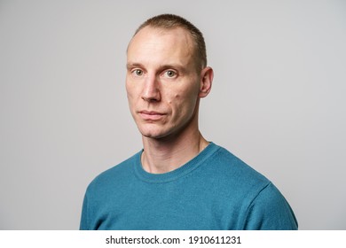 Studio Shot Portrait Of Adult Serious Caucasian Man With Short Blonde Hair In Front Of White Wall In Blue Sweater 35 Years Old