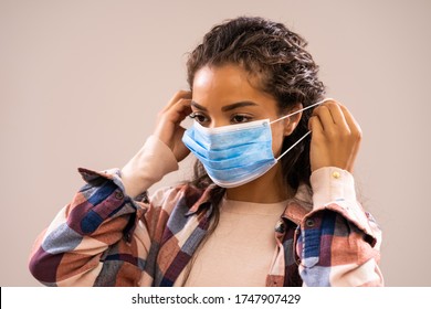 Studio shot portrait of beautiful african-american ethnicity woman who is putting protective mask. - Shutterstock ID 1747907429