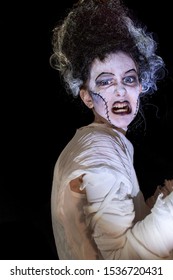 Studio Shot Portrait Of Young Girl In Costume Dressed As A Halloween, Cosplay Of Scary Bride Of Frankenstein Pose On Isolated Black Background