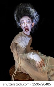 Studio Shot Portrait Of Young Girl In Costume Dressed As A Halloween, Cosplay Of Scary Bride Of Frankenstein Pose On Isolated Black Background