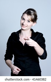 studio shot portraits of a young and cute and expressive woman on a blue grey background pointing his finger