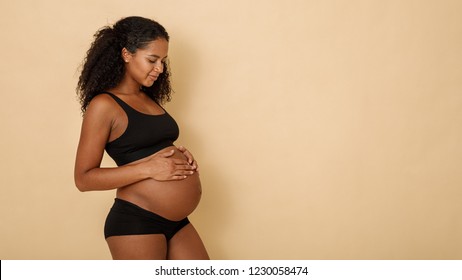 Studio shot of a pregnant woman looking on her belly, copy space