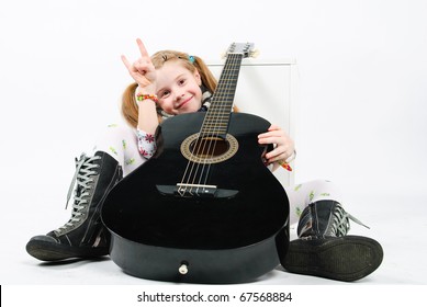 Studio Shot Of Pretty Little Girl Playing Black Acoustic Guitar