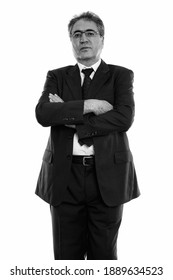 Studio shot of senior Persian businessman standing and wearing eyeglasses with arms crossed