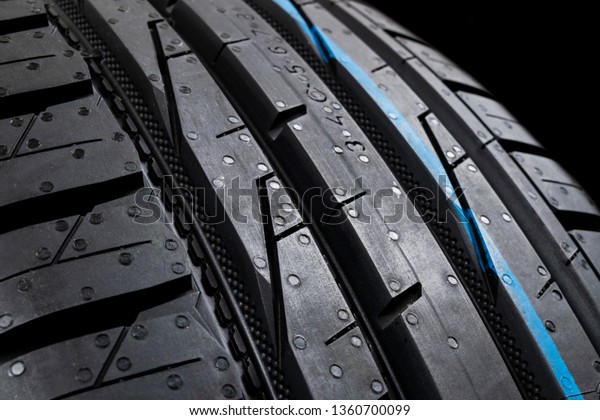 Studio shot of set of summer car tires on black\
background. Tire stack background. Car tyre protector close up.\
Black rubber tire. Brand new car tires. Close up black tyre\
profile. Car tires in a\
row