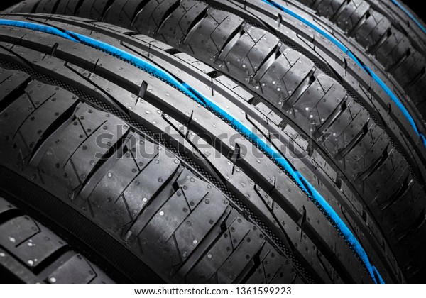 Studio shot set of a summer car tires on black\
background. Tire stack background. Car tyre protector close up.\
Black rubber tire. Brand new car tires. Close up black tyre\
profile. Car tires in a\
row