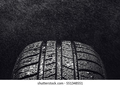Studio shot of a set of summer, fuel efficient car tires on black background. Covered in wated droplets, rain or aquaplaning concept. Contrasty lighting and shallow depth of field