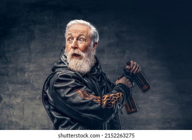Studio shot of shocked grandfather motorcyclist with two bottles dressed in leather jacket.