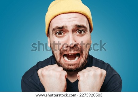 A studio shot of a shouting guy, his expression one of anger and irritation as he looks directly at the camera and lets out a violent scream. close up