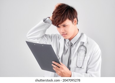 Studio Shot Of Stressed Man Doctor Holding Clipboard