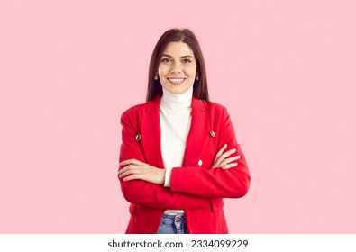 Studio shot of stylish businesswoman in smart casual outfit. Happy beautiful young business woman in red suit jacket, jeans and white turtleneck standing isolated on pink background. Fashion concept - Shutterstock ID 2334099229
