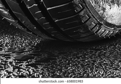 Studio shot of a summer, fuel efficient car tire on black background. Covered in wated droplets, rain or aquaplaning concept. Contrasty lighting and shallow depth of field