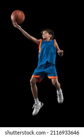 Studio Shot Of Teen Boy Playing Basketball, Throwing Ball Into Basket Isolated Over Black Background. Scoring Winning Goal. Concept Of Sport, Active Lifestyle, Health, Team Game And Ad