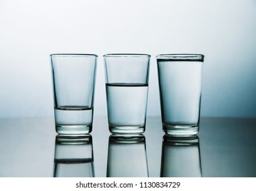 studio shot of three water glasses each one have more water than the other