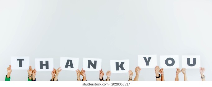 Studio shot of unrecognizable unidentified group of staff officer in corporate office holding thank you alphabet cardboard paper sign over head showing appreciation to customer on white background.