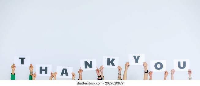 Studio shot of unrecognizable unidentified group of staff officer in corporate office holding thank you alphabet cardboard paper sign over head showing appreciation to customer on white background.
