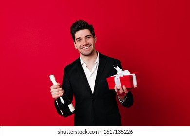 Studio shot of well-dressed man with bottle of champagne. Smiling male model posing in valentine's day. - Powered by Shutterstock