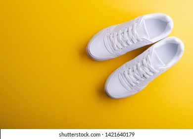 A Studio Shot Of White Running Shoes On Yellow Background. Flat Lay.