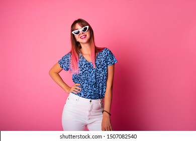 Studio Shot Of Woman In Blue Leopard T-shirt Isolated On Pink Background.Portrait Of A Cheerful Young Girl In Casual Fashion Look Looking At Camera And Winking Isolated Over Pink Background.Copy Space