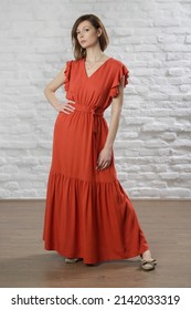 Studio Shot Of Woman In Long Orange Summer Dress.	