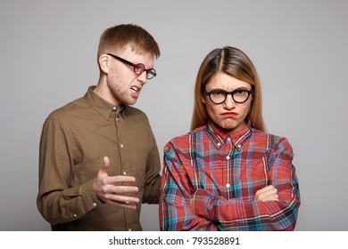Studio shot of you European couple having argument: bearded guy in oval glasses trying to convince his stubborn girlfriend who is crossing arms and making displeased grimace, expressing disagreement
