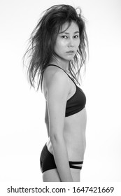 Studio Shot Of Young Asian Woman Standing In Her Underwear With Messy Hair Against White Background