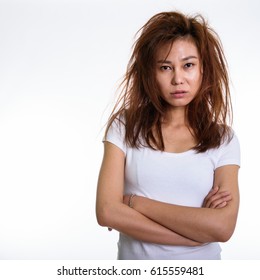 Studio Shot Of Young Asian Woman With Arms Crossed And Messy Hair Against White Background