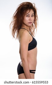 Studio Shot Of Young Asian Woman Standing In Her Underwear With Messy Hair Against White Background