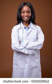 Studio Shot Of Young Beautiful African Zulu Woman Doctor Against Brown Background